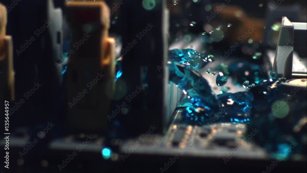 Blue liquid rushes over a computer's motherboard like a tsunami.