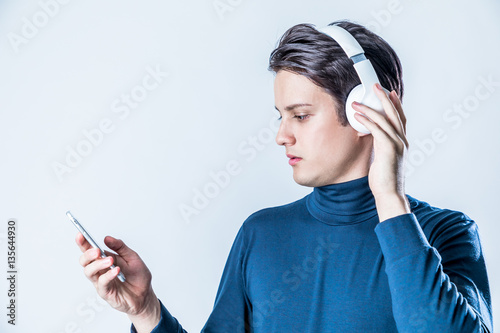 young man wearing wireless headphone and listening to music with smart phone