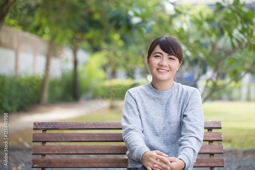 Happy woman sitting on the bench at park