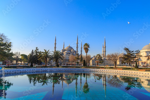 Blue mosque with reflection on fountain in sultanahmet square.