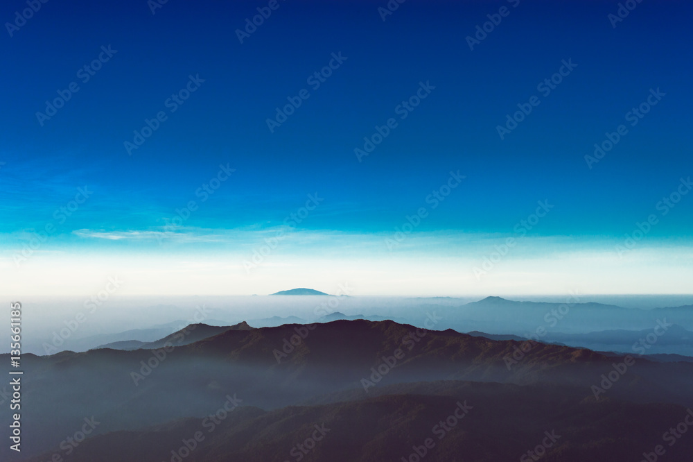 Scenic destination view after sunrise over clouds with mountains