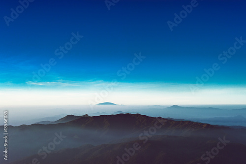 Scenic destination view after sunrise over clouds with mountains