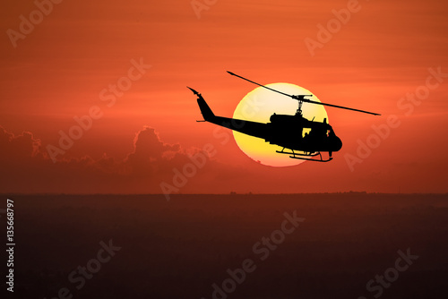 Flying helicopter silhouettes on sunset background.
 The patrol helicopter flying in the twilight sky. 
