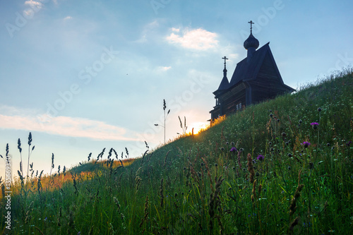 Wooden church on the top of the hill. Vershinino village sunset view. Arkhangelsk region, Northern Russia. photo