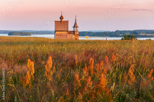 Wooden church on the top of the hill. Vershinino village sunset view. Arkhangelsk region, Northern Russia. photo