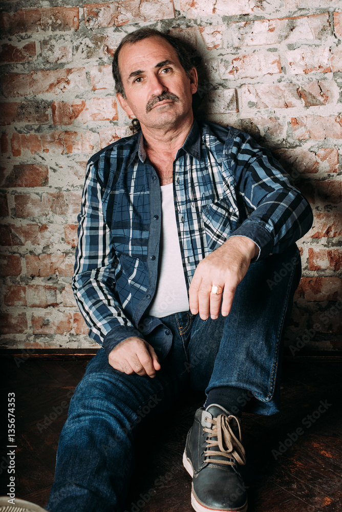 Handsome middle aged man is dressed in a casual clothing. Red brick wall background. Handsome middle aged man is dressed in a casual clothing. Red brick wall background.