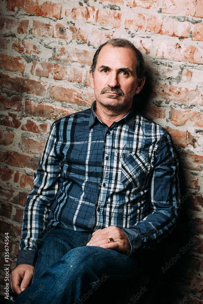 Handsome middle aged man is dressed in a casual clothing. Red brick wall background. Handsome middle aged man is dressed in a casual clothing. Red brick wall background.