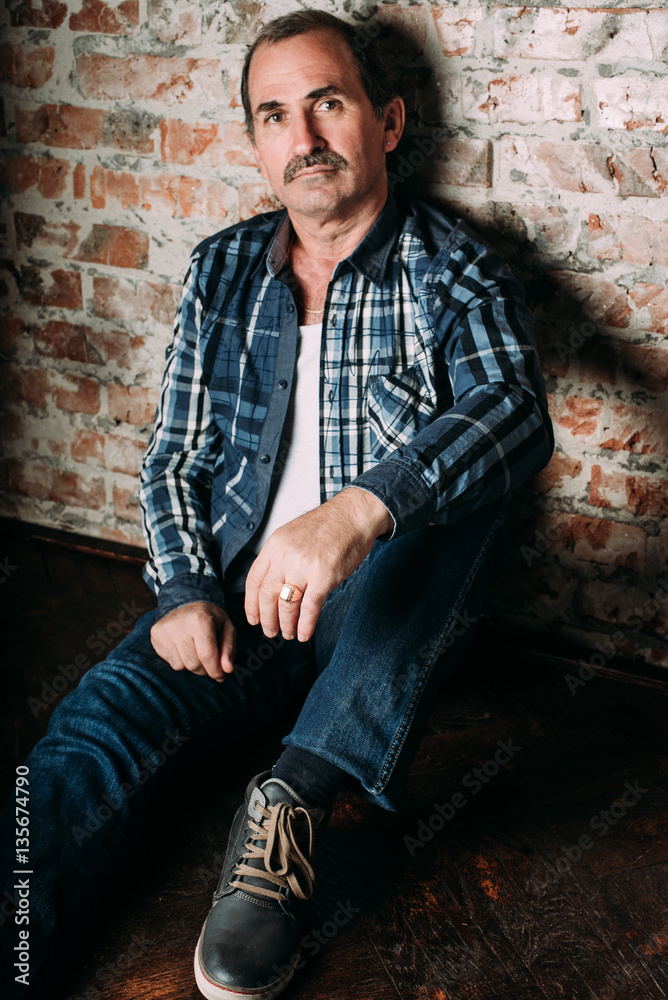 Handsome middle aged man is dressed in a casual clothing. Red brick wall background. Handsome middle aged man is dressed in a casual clothing. Red brick wall background.