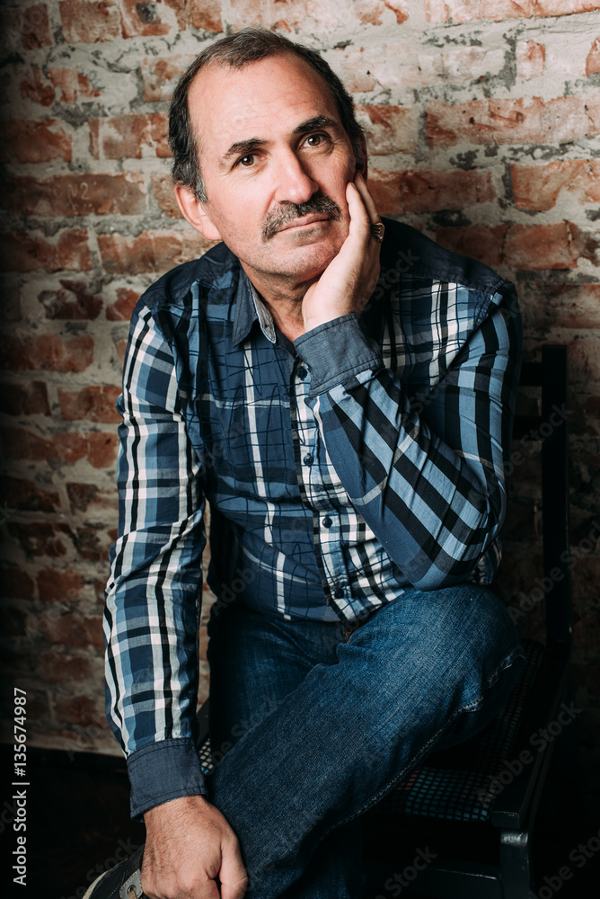 Handsome middle aged man is dressed in a casual clothing. Red brick wall background. Handsome middle aged man is dressed in a casual clothing. Red brick wall background.