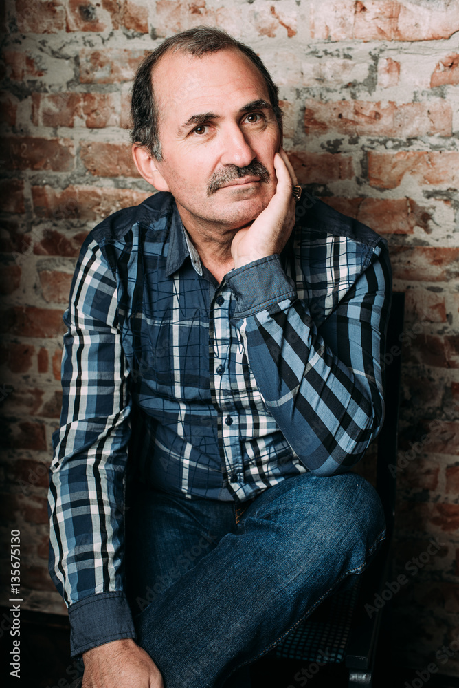 Handsome middle aged man is dressed in a casual clothing. Red brick wall background. Handsome middle aged man is dressed in a casual clothing. Red brick wall background.