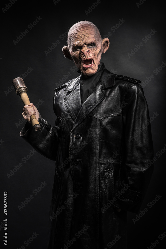 Angry baboonish man in black clothes on dark background