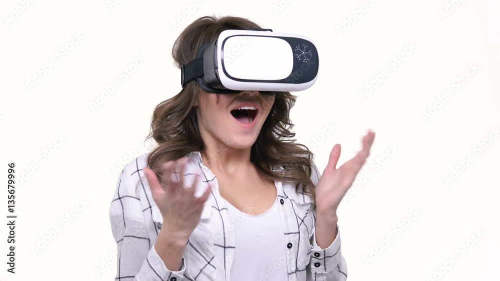 Attractive young woman wearing virtual reality goggles isolated over white Attractive young woman wearing virtual reality goggles isolated over white