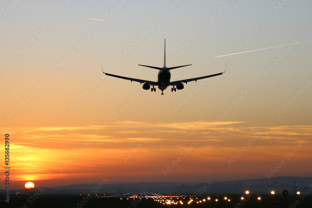 Plane lands at an airfield on the background of sunset