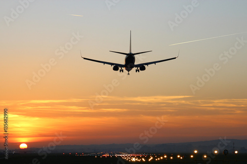 Plane lands at an airfield on the background of sunset © Bogdan