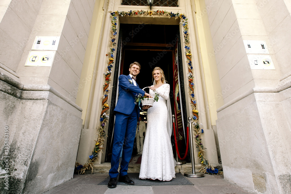Bride holds white basket while groom takes sweets from it Bride holds white basket while groom takes sweets from it