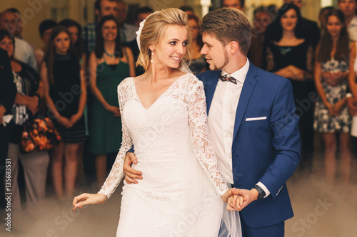 Groom hugs bride from behind during their first dance