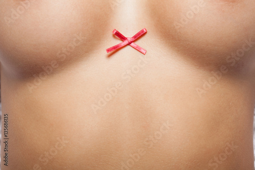 Woman breast with little red bow. photo