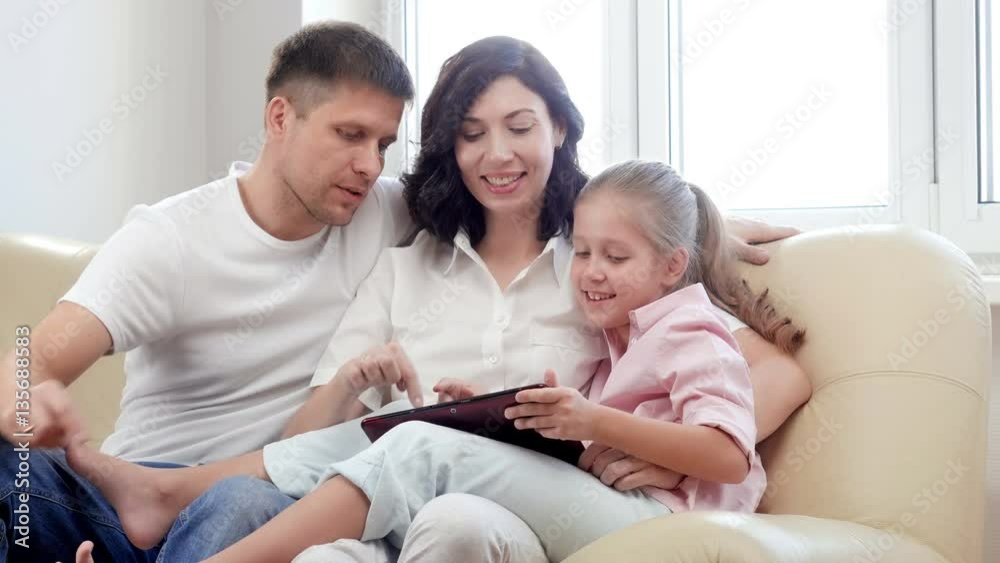 Family using digital tablet. Parents showing digital tablet to their daughter at home. Family using digital tablet. Parents showing digital tablet to their daughter at home.