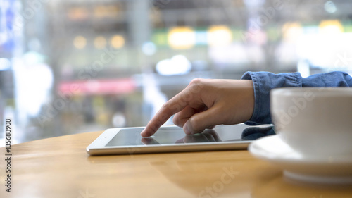 Tablet close up photo with man hands macro shot. using tablet in the cafe and drinking tea. Blurred background with lens flare effects. man using tablet computer and drinking coffee.