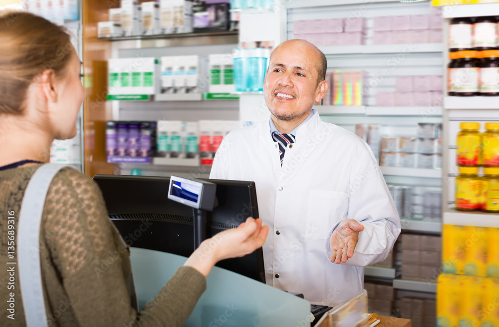 Pharmaceutist helping adult woman in drugstore