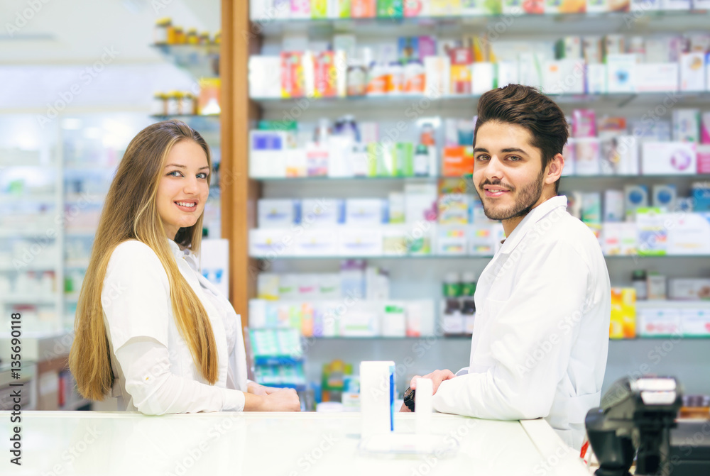 Female and male pharmacists in pharmacy smiling