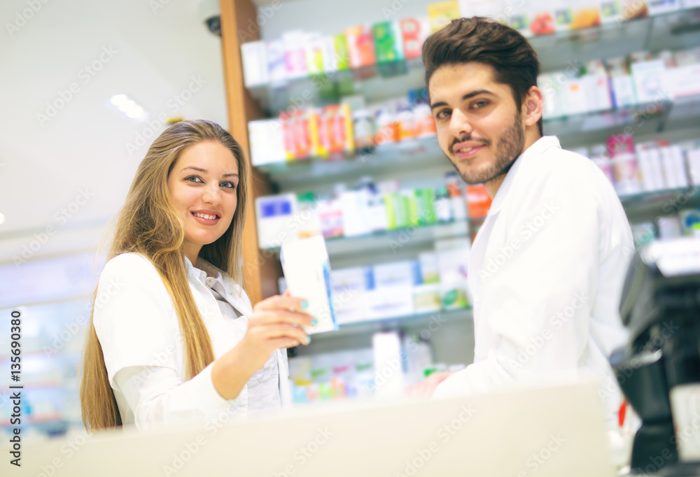 Female and male pharmacists in pharmacy smiling