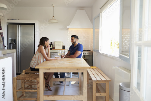 Adult couple talk and drink wine in the kitchen, full length