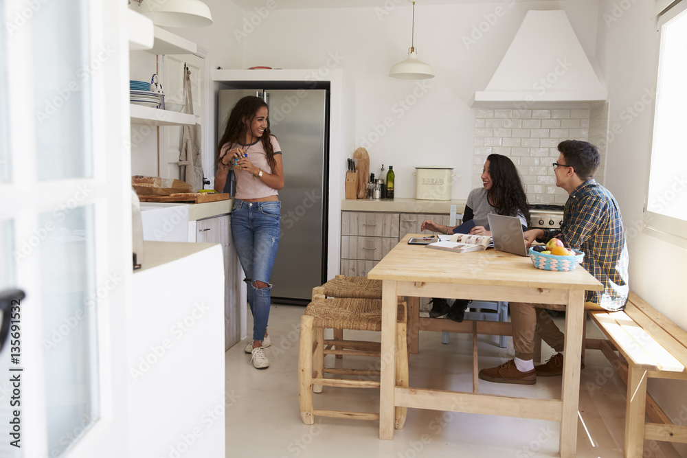 Teenage friends hanging out and studying together in kitchen