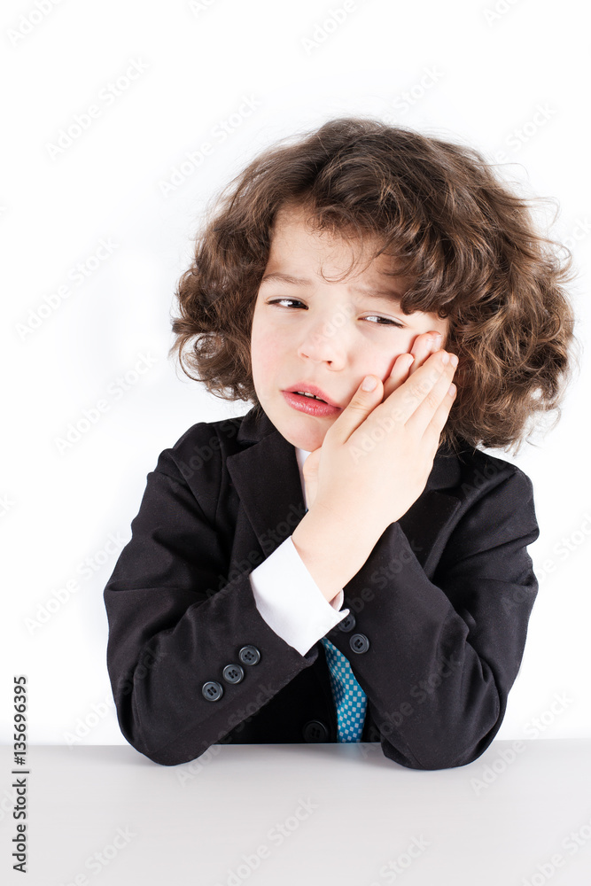 Little curly manager in a business suit sitting, crying and holding both hands on the cheek. White background. Little curly manager in a business suit sitting, crying and holding both hands on the cheek. White background.