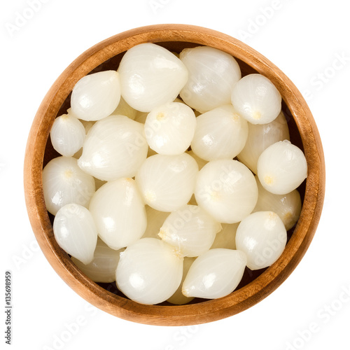 Pickled silverskin onions in wooden bowl. Small white onions pickled in a solution of vinegar and salt, a preserved vegetable. Isolated macro food photo close up from above on white background.