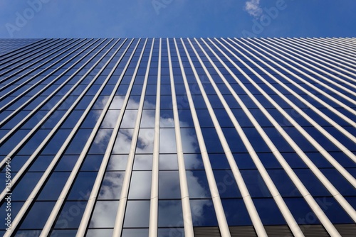 高層ビルのガラスに映る白い雲 天空に聳える高層ビルが青空を突き抜けるようでダイナミックな印象だ。
