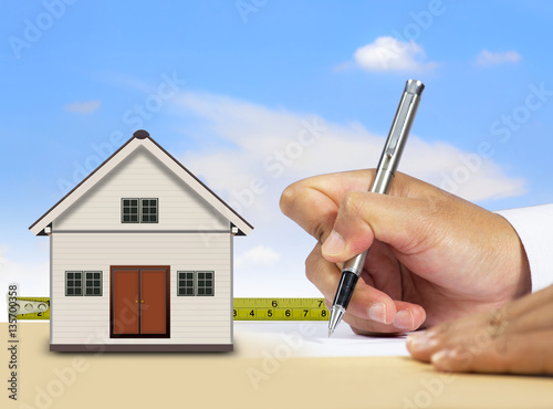 Businessman signing document with little house