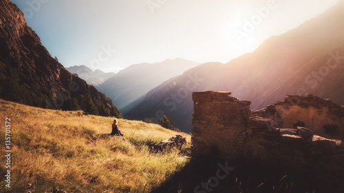 Dziewczyna siedzi na kamieniu i ogląda wschód słońca w górach