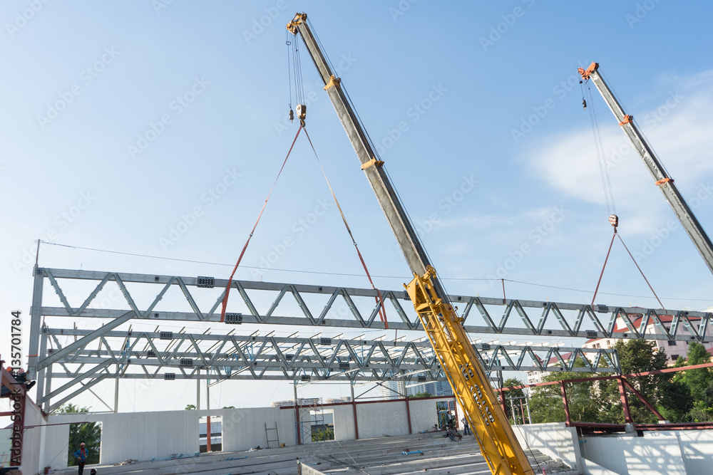 Construction site crane is used to placing steel roof frame
