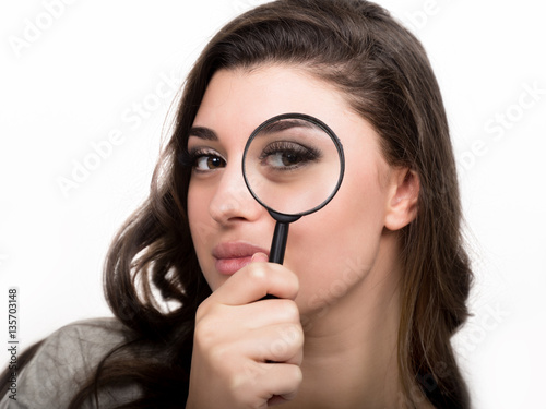 portrait of young woman looking through magnifying glass