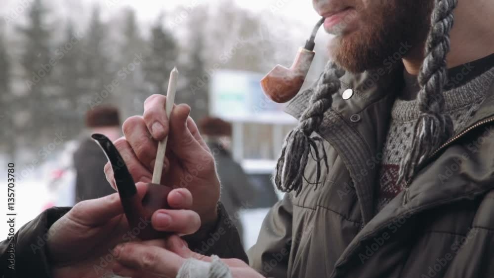 two man with a beard in the winter get a light pipe