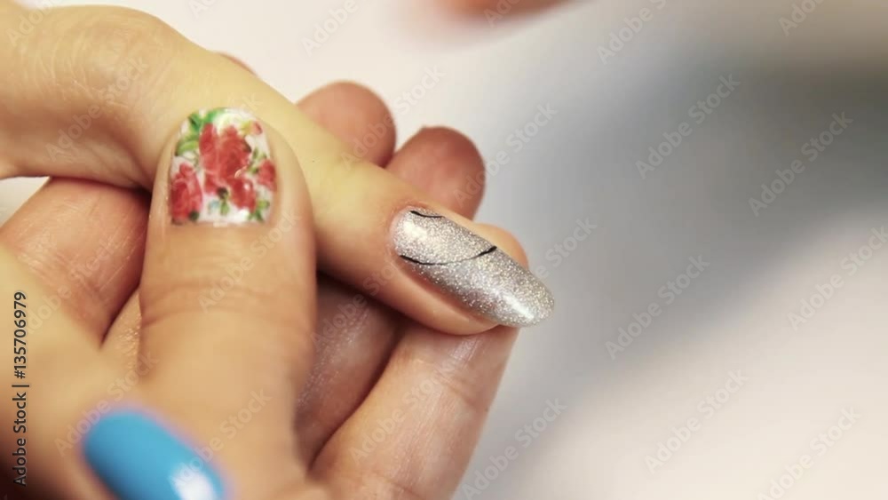 Cosmetic shop manicure session, woman hand painting black pattern on silver nail polish, close up