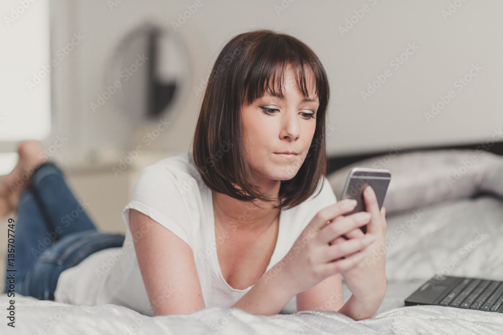 beautiful woman writes sms on smartphone in white tshirt and blu beautiful woman writes sms on smartphone in white tshirt and blu