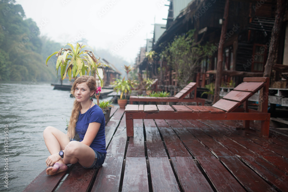 image of happy young woman at beach house on the River Kwai in Thailand