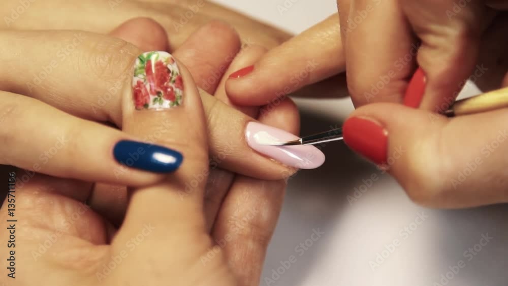 Beauty shop manicure session, woman hand painting colorful pattern on nail polish, close up