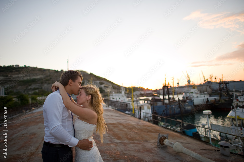 Happy bride and groom hugging on a yacht - looking into each other
evening yellow sun