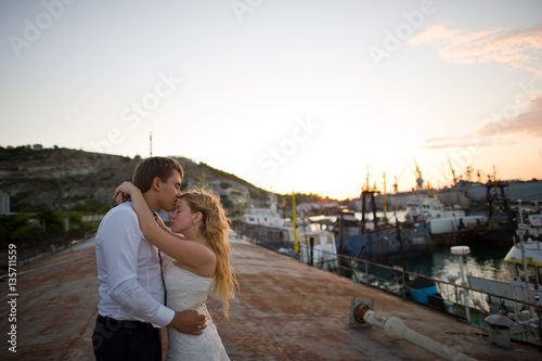 Happy bride and groom hugging on a yacht - looking into each other evening yellow sun