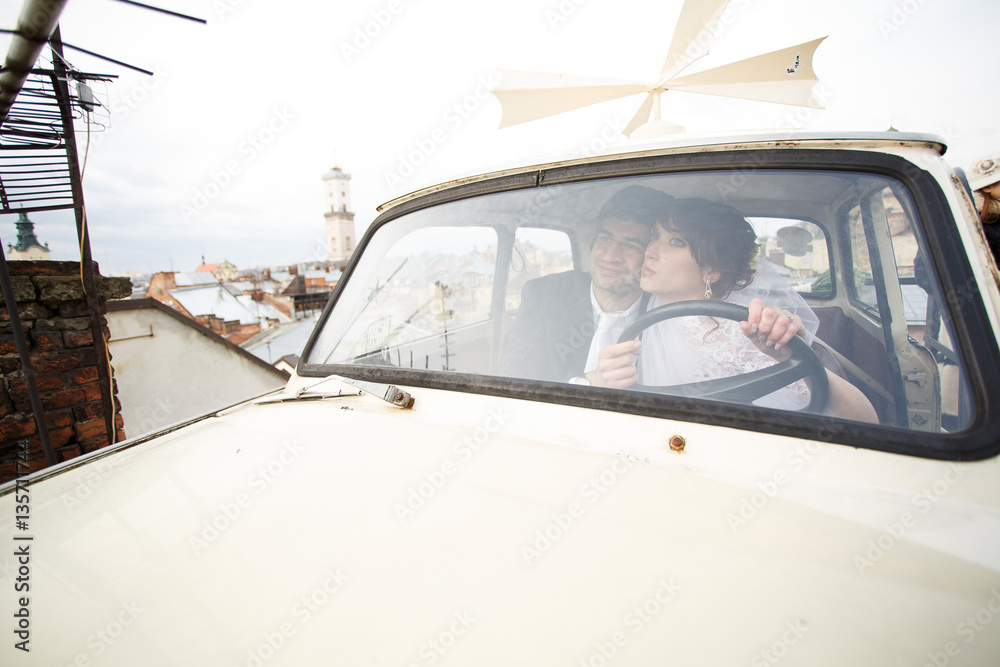 Happy stylish newlywed couple posing in retro car Happy stylish newlywed couple posing in retro car