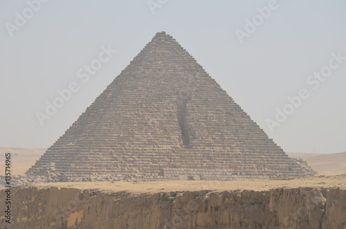 Pyramid in sand dust under gray clouds