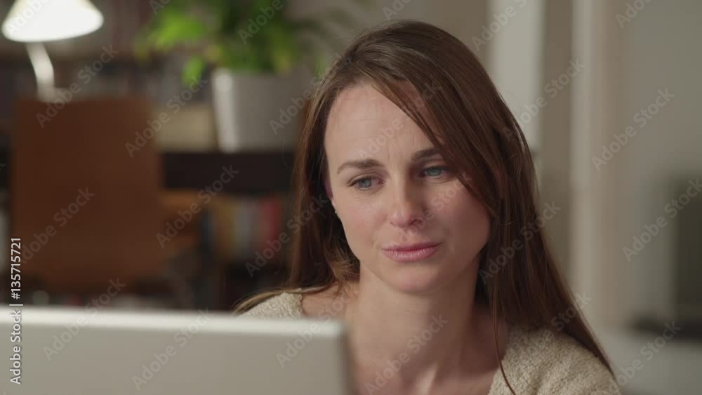 Young woman watches videos on internet in her laptop at home. She watches very concentrated and serious. Dolly shot to the right. Young woman watches videos on internet in her laptop at home. She watches very concentrated and serious. Dolly shot to the right.