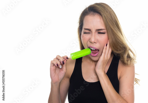 woman with hypersensitive teeth eating ice lolly, isolated on wh