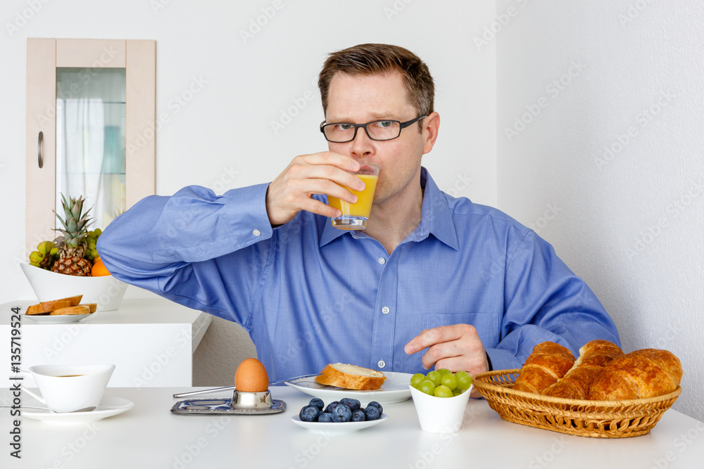 Mann trinkt Orangensaft zum Frühstück Mann trinkt Orangensaft zum Frühstück