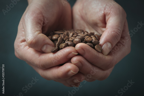 Lonely woman drinking coffee in the morning, top view of female hands holding cup of hot beverage on wooden desk, retro toned