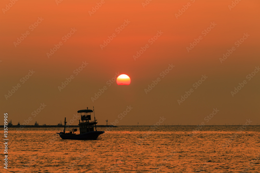 Orange sky with sunset over sea , shore and fishing boat