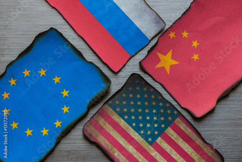 Chinese, European, Russian and American flags side by side on brushed metal background photo